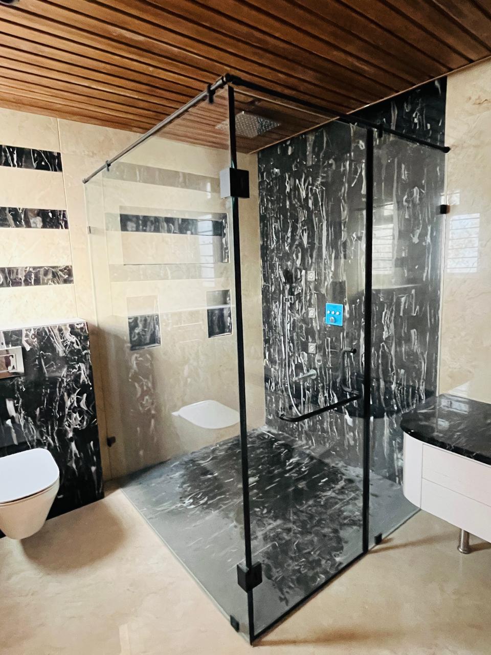 L-shaped glass enclosure with matte black hardware in Chennai home